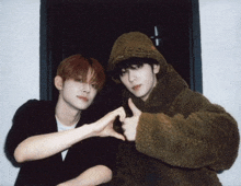 two young men are making a heart shape with their fingers