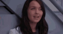 a woman in a white lab coat is standing next to a staircase .