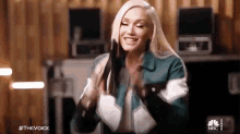 a woman with long blonde hair is smiling and holding her hair in a room .