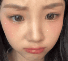 a close up of a woman 's face with a tear coming out of her eye