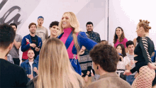 a woman is dancing in front of a crowd of people in a room .