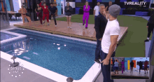 a group of people standing in front of a swimming pool with tvreality written on the bottom of the screen