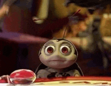 a cartoon bug with big eyes is sitting on a table next to a red ball .