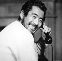 a black and white photo of a man talking on a telephone