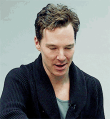 a close up of a man wearing a black sweater with his eyes closed