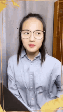 a woman wearing glasses and a blue shirt looks to the side