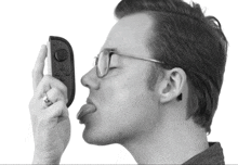 a man with glasses is sticking his tongue out while holding a game controller