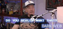 a man is sitting in front of a microphone with the words " do you really want that " written on the screen behind him
