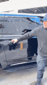 a man opens a car door in front of a sign that says " one "