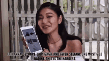 a woman is holding a cell phone in front of a white railing and smiling .