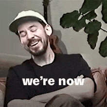 a man is sitting on a couch with his arms crossed and the words we 're now above him