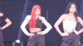 a woman with red hair is standing next to another woman in a white tank top