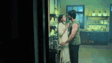 a man and woman are kissing in a kitchen .