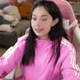 a woman in a pink jacket is sitting in a chair