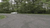 a white car is driving down a road in a parking lot