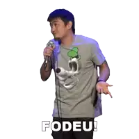 a man wearing a gray shirt with a skull on it stands in front of a microphone