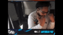 a man wearing glasses and headphones is sitting in front of a screen that says ' aster ' on it .