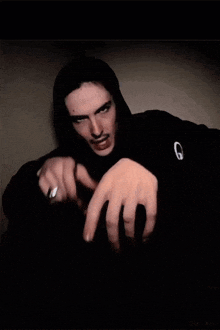 a man wearing a black hoodie with the letter g on the front