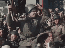 a man in a helmet stands in front of a crowd of soldiers