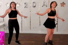 two women are dancing in front of a sign that says roa