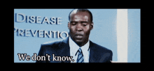 a man stands in front of a sign that says disease prevention we don 't know