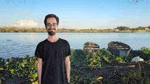 a man in a black shirt stands in front of a body of water