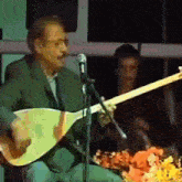 a man playing a guitar in front of a microphone