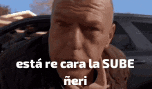 a man is sitting in a car with his eyes closed and the words está re cara la sube written on his face