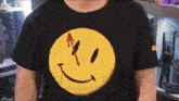 a person wearing a black shirt with a yellow smiley face with a red arrow pointing up