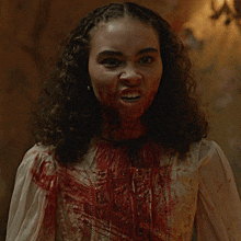a woman with blood on her face is wearing a white top