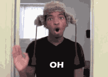 a man wearing a fur hat and a black shirt is standing in a doorway and making a surprised face .