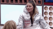 a woman in a silver jacket is talking to another woman