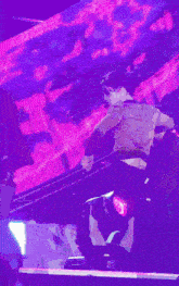 a man stands in front of a stage with a purple background
