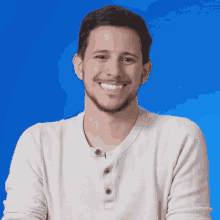 a man in a white shirt is smiling in front of a blue background that says " brawl stars now "