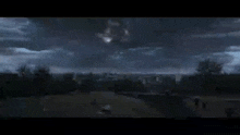 a person is standing on top of a hill looking at a group of lights flying in the night sky .