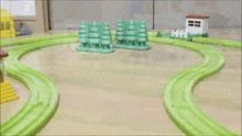 a toy train is going down a track with green trees