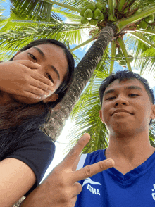 a man wearing a blue shirt that says atma stands next to a woman covering her face