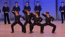 a group of men in navy uniforms are performing a dance