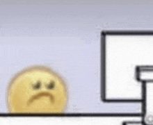 a sad smiley face is sitting on a desk next to a computer monitor .