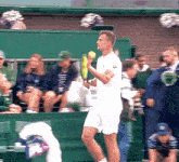 a man in a white shirt with the word lacoste on it holds a tennis racket