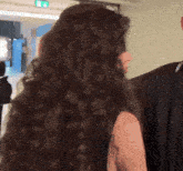 a woman with long curly hair is standing next to a man in a black jacket .