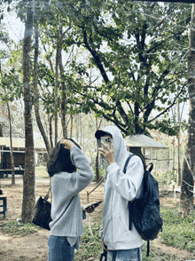 a man in a hoodie is taking a picture of a woman in a grey sweater