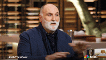 a man with a beard is sitting at a table with nbc written on the bottom