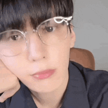 a close up of a young man wearing glasses and a black shirt .