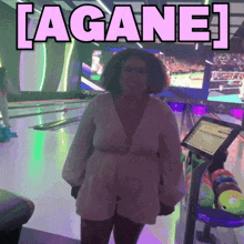 a woman standing in a bowling alley with a sign that says lagan