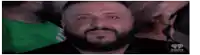 a man with a beard is smiling at the camera while sitting in a crowd of people .
