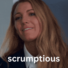 a woman in a suit and white shirt is smiling with the word scrumptious in the corner