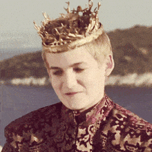 a young man wearing a crown on his head looks down