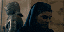 a nun is standing next to a knight in armor .