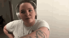 a woman wearing headphones looks at the camera